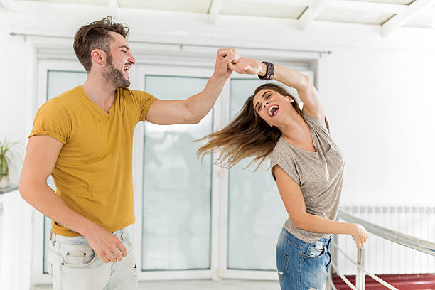 Young happy couple dancing at home and laughing.